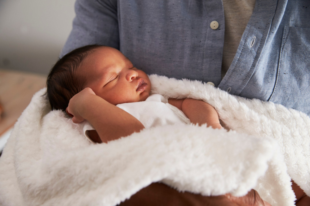Close up of a new born baby being heldin a white blanket