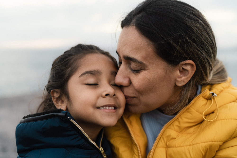 Mum kissing her daughter on the cheek